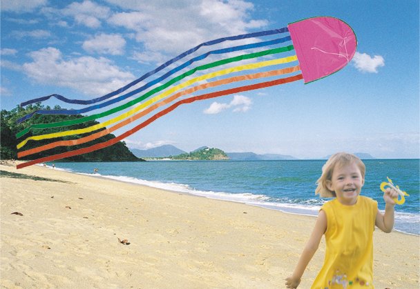 beautiful girl flying a pink jellyfish with 6 long rainbow colored tails on the beach at Cairns in North Queensland