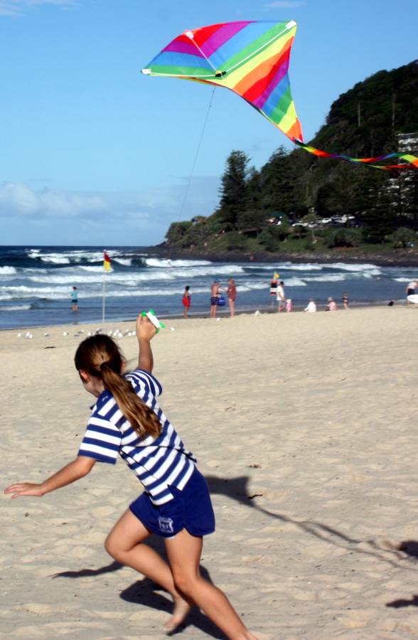 young girl flying rainbow colored diamond kite at Burleigh Heads beach on the Gold Coast